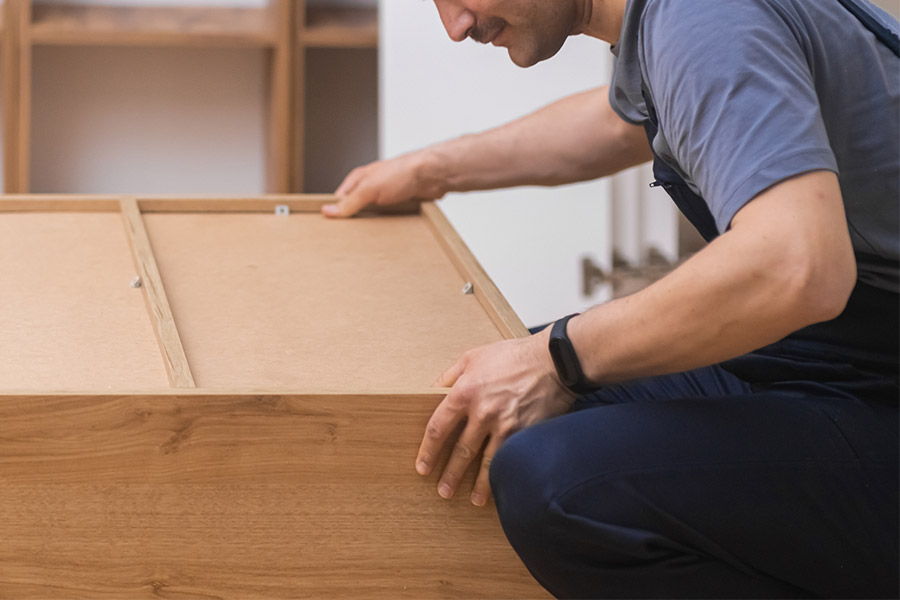 Furniture assembly and installation services man in professional uniform wooden cabinet